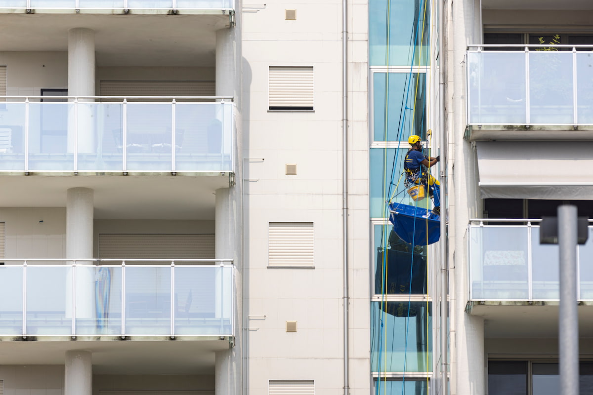 Ouvrier Acrobatica sur une corde lors de l'entretien des terrasses de copropriétés