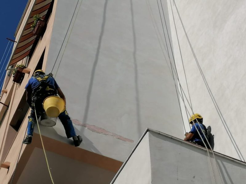 Ouvrier en grimpant sur une corde pour rénovation thermique