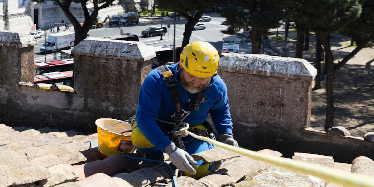 Un ouvrier travaille sur le toit, installant l'isolation extérieure pour améliorer le confort thermique et l'efficacité énergétique de la maison.