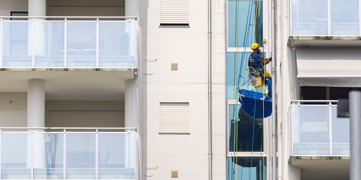 Ouvrier d'Acrobatica en action sur un immeuble contemporain, réalisant le ravalement de façade en copropriété.