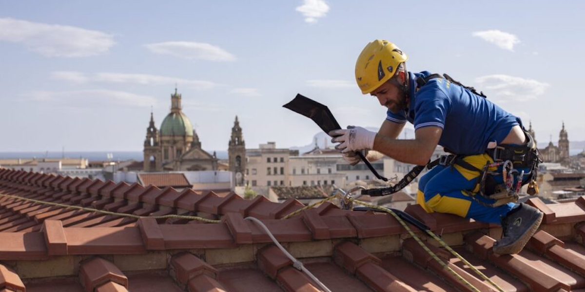 Ouvrier de l'entreprise acrobatique lors de l'installation d'une toiture sur un bâtiment