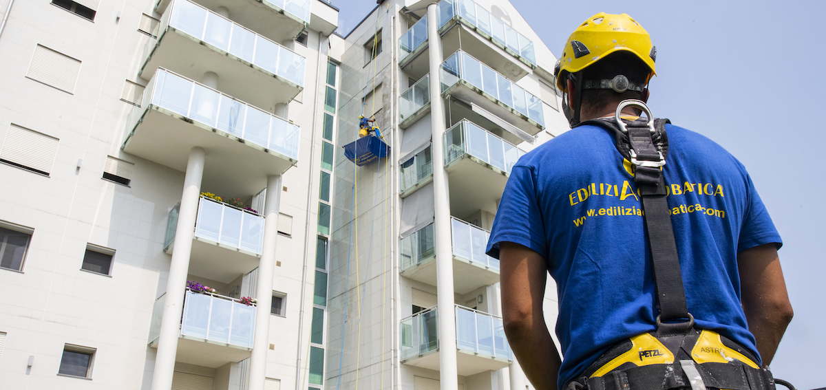 Un ouvrier supervise l'installation des panneaux solaires en regardant de bas en haut vers le toit du bâtiment, dans le cadre des travaux déductibles d'impôts.