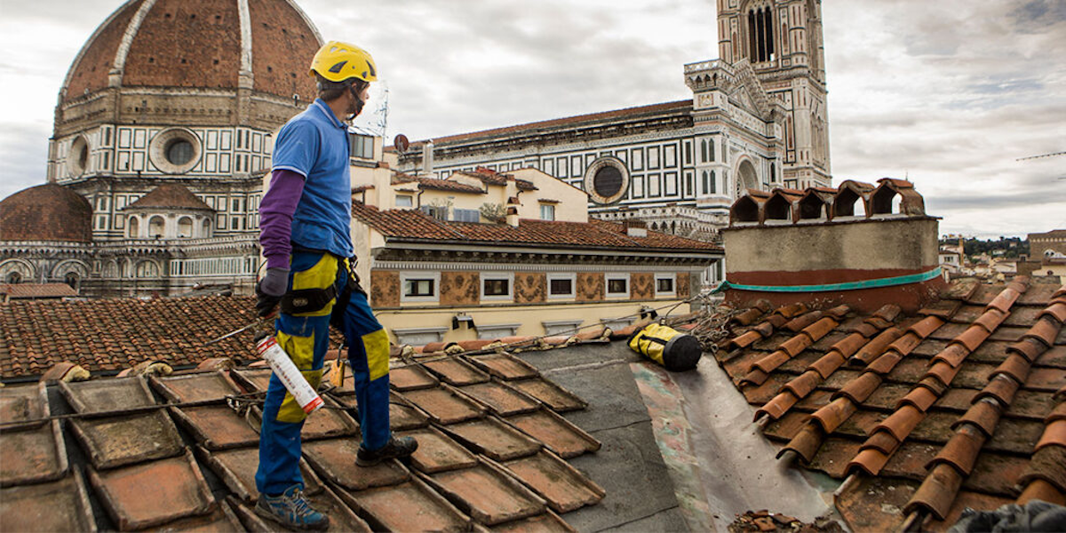 Ouvrier scrutant l'horizon depuis les toits de Florence, symbolisant les opportunités de rénovation offertes par le crédit d'impôt.