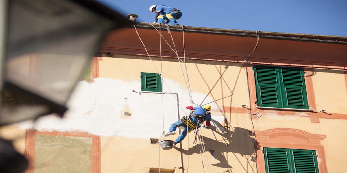 Deux ouvriers appliquant une isolation thermique sur le toit d'un bâtiment, pour améliorer l'efficacité énergétique et réduire les pertes de chaleur