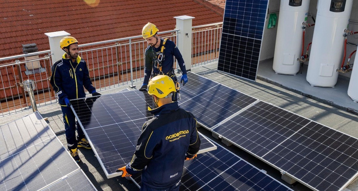 Trois ouvriers installent des panneaux solaires sur le toit d'un bâtiment dans le cadre de travaux déductibles d'impôts.