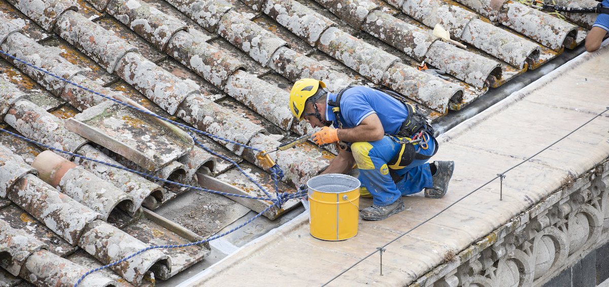 Ouvrier travaillant sur le toit du Duomo d'Orvieto, effectuant des travaux de maintenance et de restauration sur la structure historique tout en profitant de la vue panoramique.

