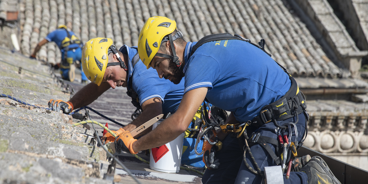 Ouvriers acrobatiques lors de la rénovation d'un revêtement thermique en toiture