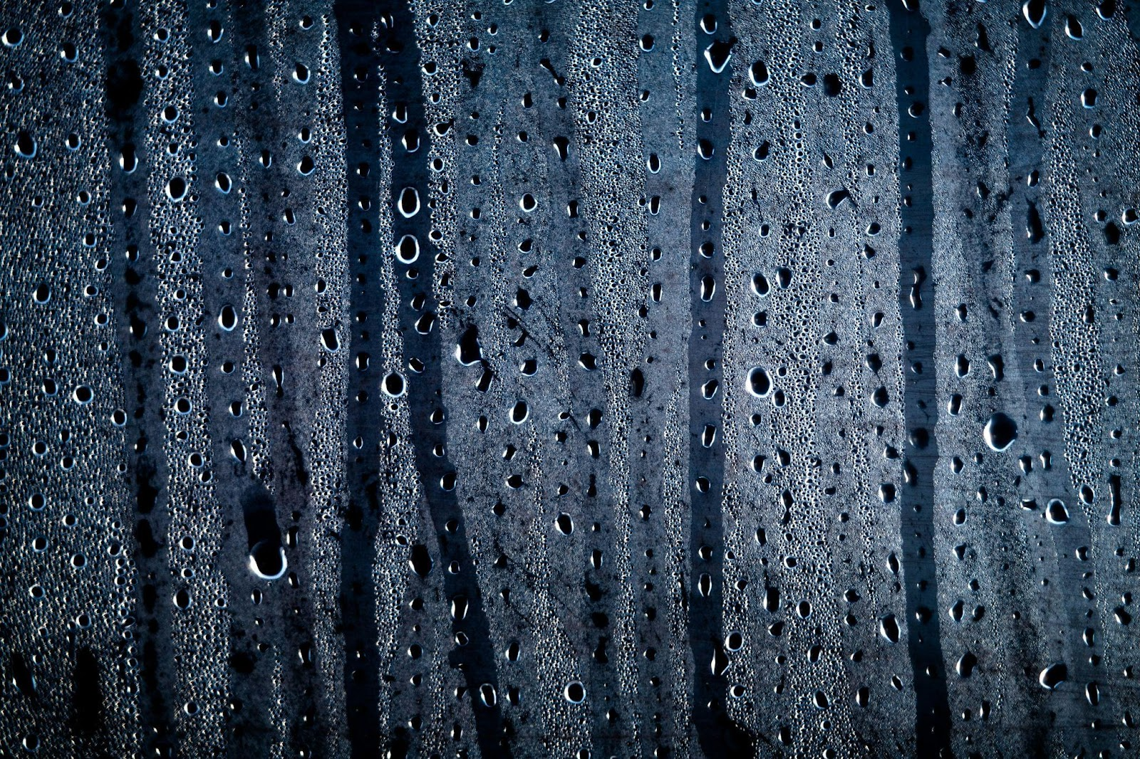 Condensation sur une vitre qui forme de grosses gouttes et coule