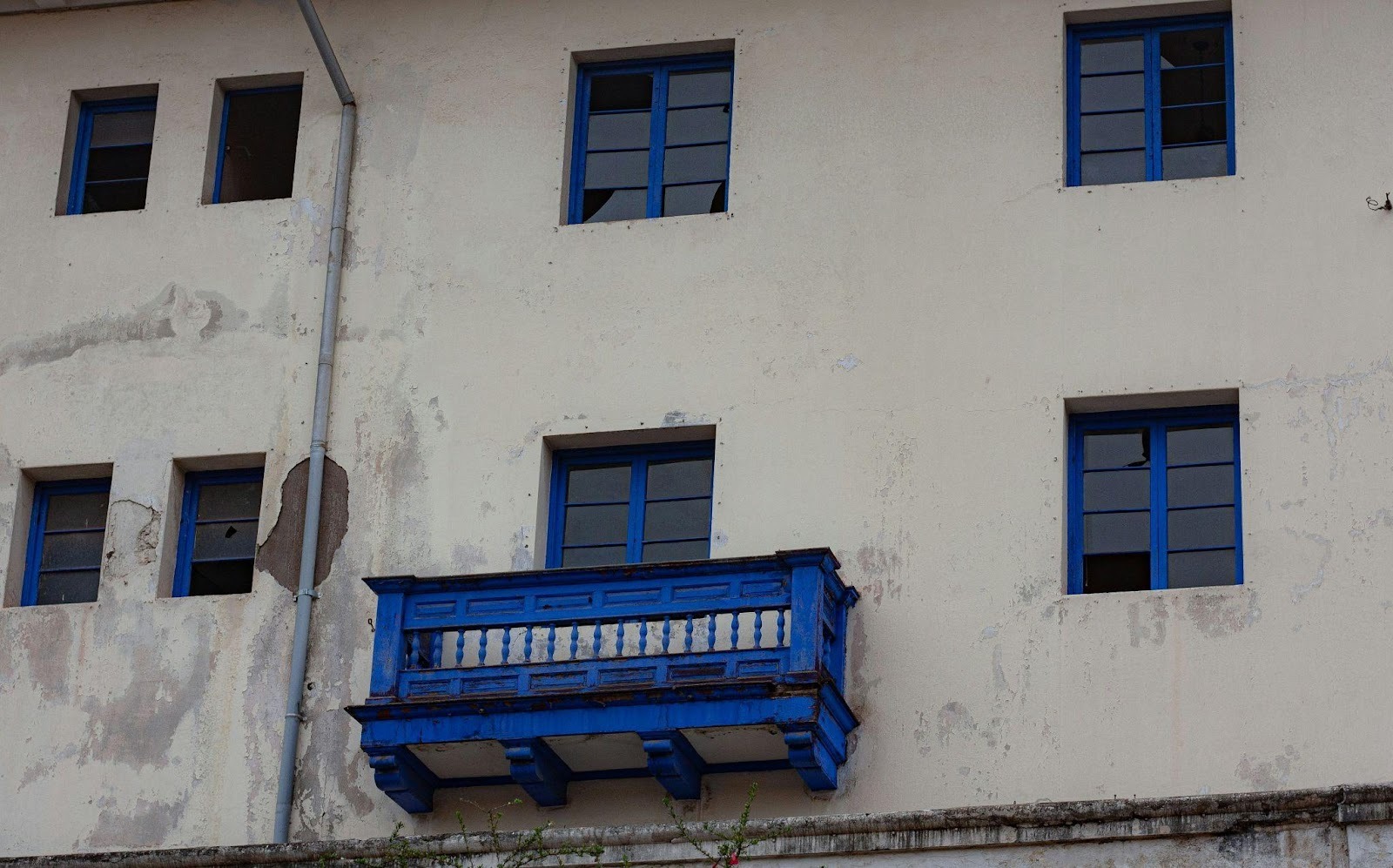 Balcon bleu sur façade blanche avec traces d’usure