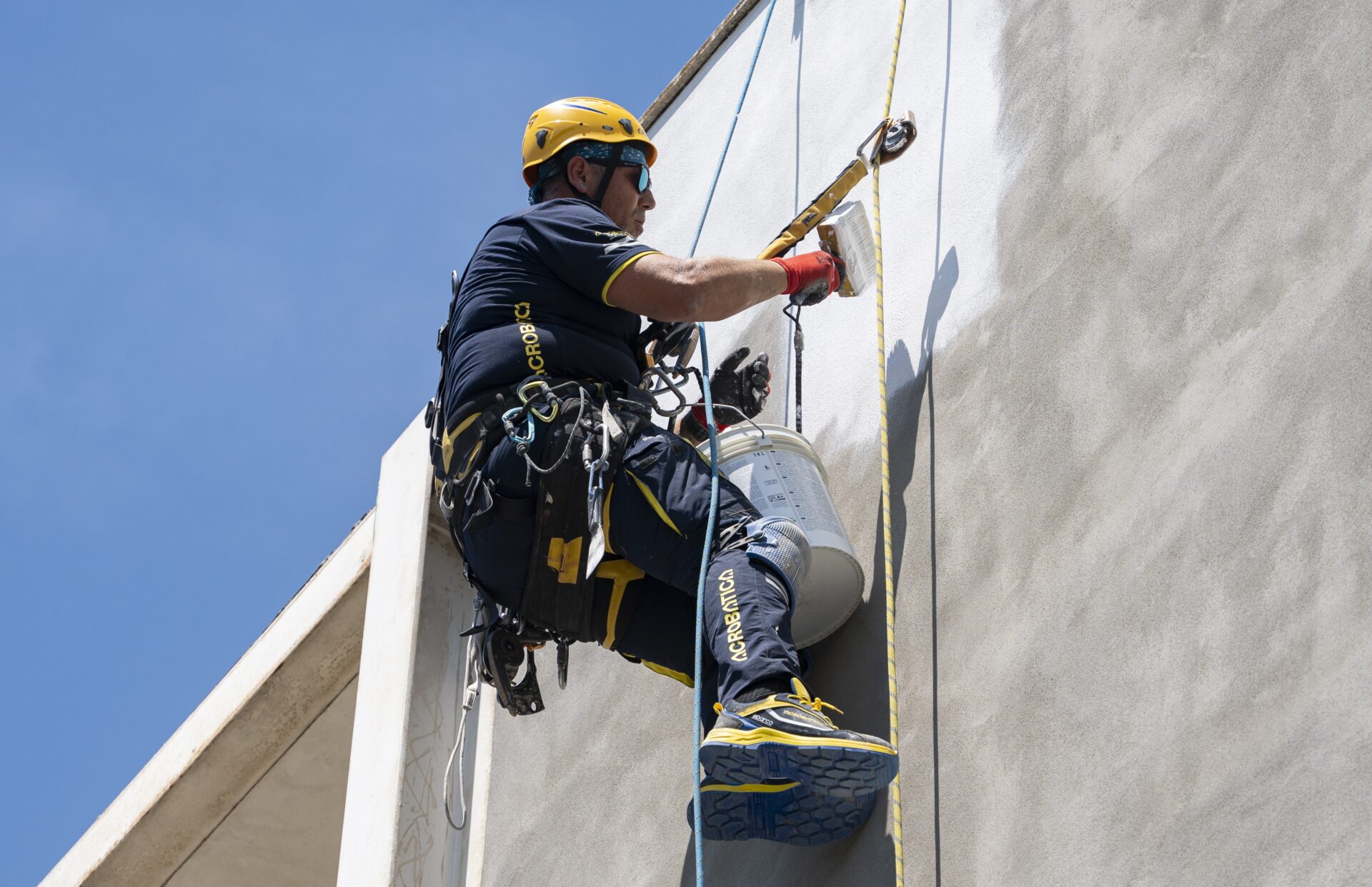 Un ouvrier en tenue blanche sur un mur de couleur vive.