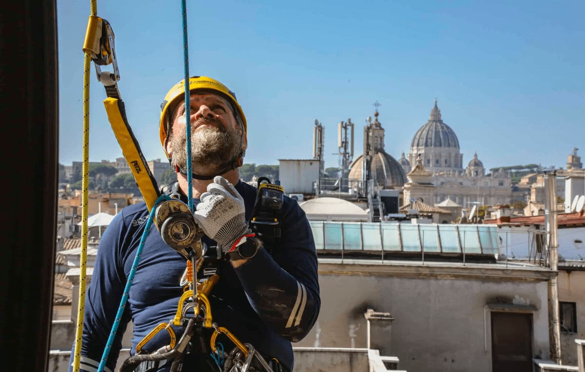  Ouvrier cordiste d'EdiliziAcrobatica vu de face, suspendu sur sa corde au milieu de bâtiments historiques et de palais anciens à Florence.