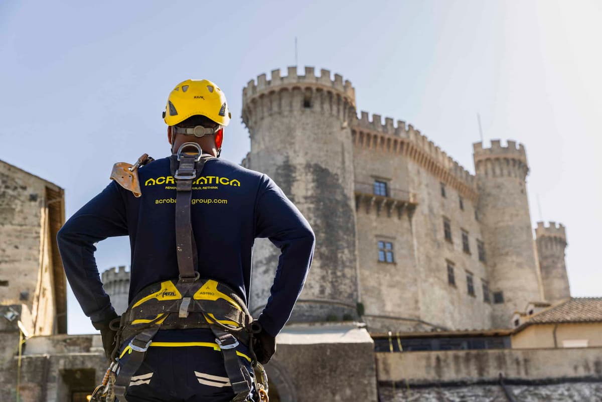Ouvrier cordiste d'EdiliziAcrobatica vu de dos, pour rénover le château historique de Sirmione au bord du lac de Garde.