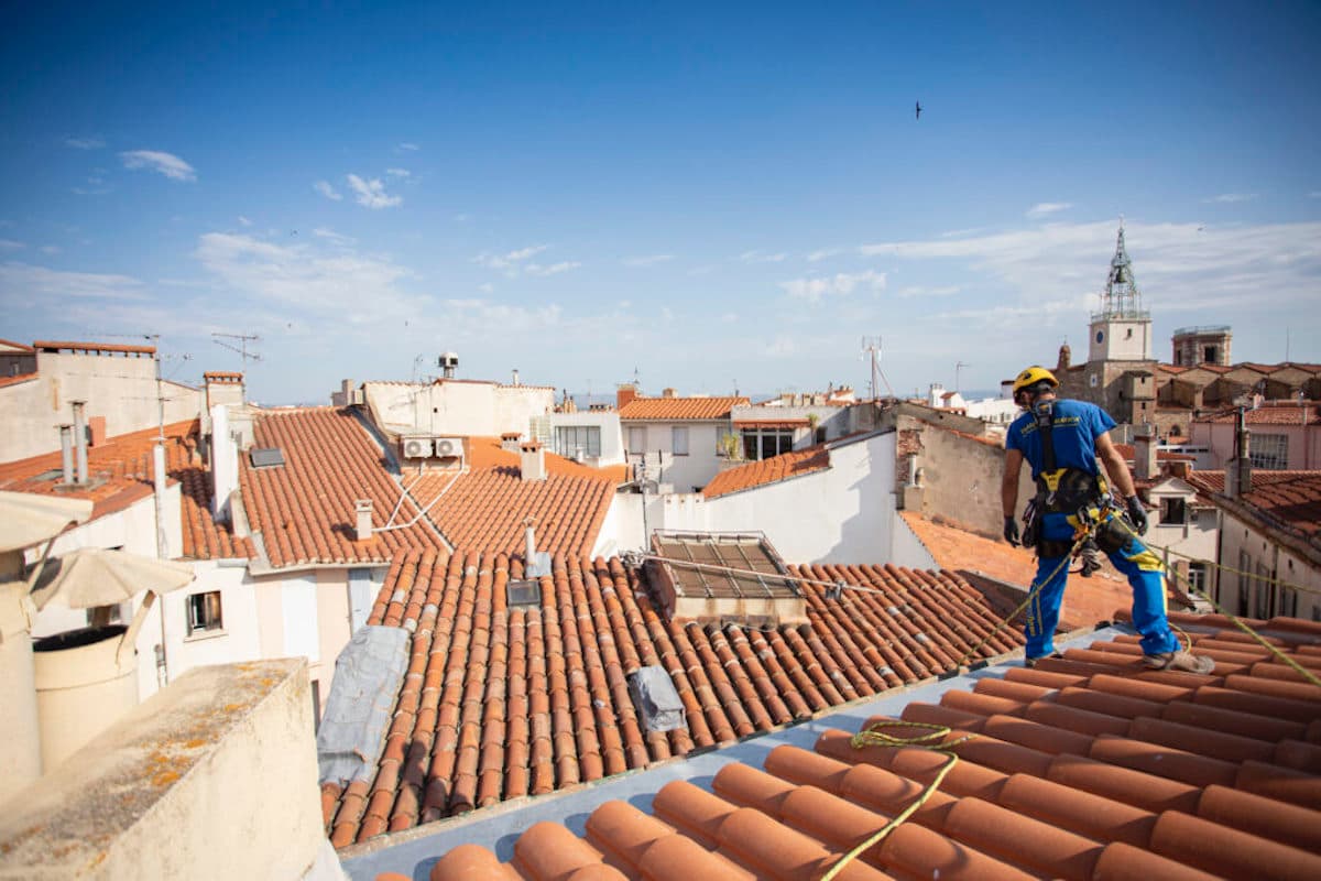 Artisans d'Acrobatica suspendus sur cordes pour inspecter les tuiles et prévenir l'affaissement de la toiture d'une maison.